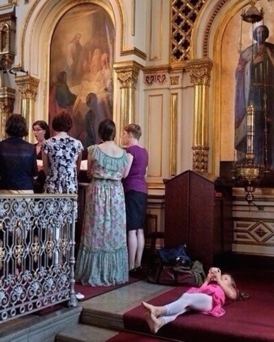 niña acostada en el piso de la iglesia aburrida