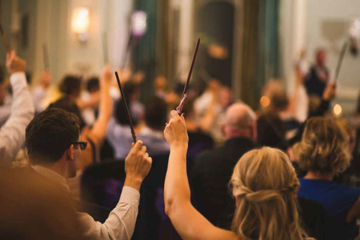 invitados de la boda al estilo Harry Potter con varitas mágicas en sus manos 