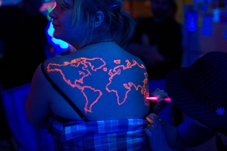 tatuaje color naranja que brilla en la oscuridad con el diseño de un mapa mundial