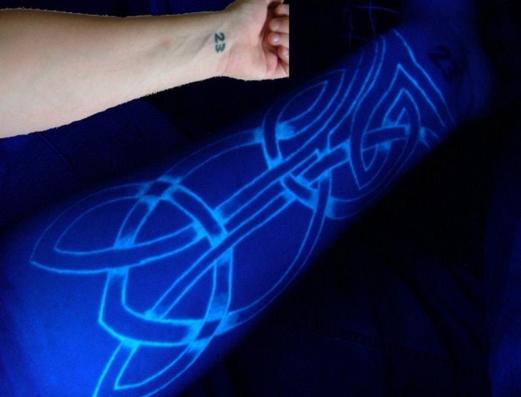 tatuaje fluorescente en un brazo con lineas 