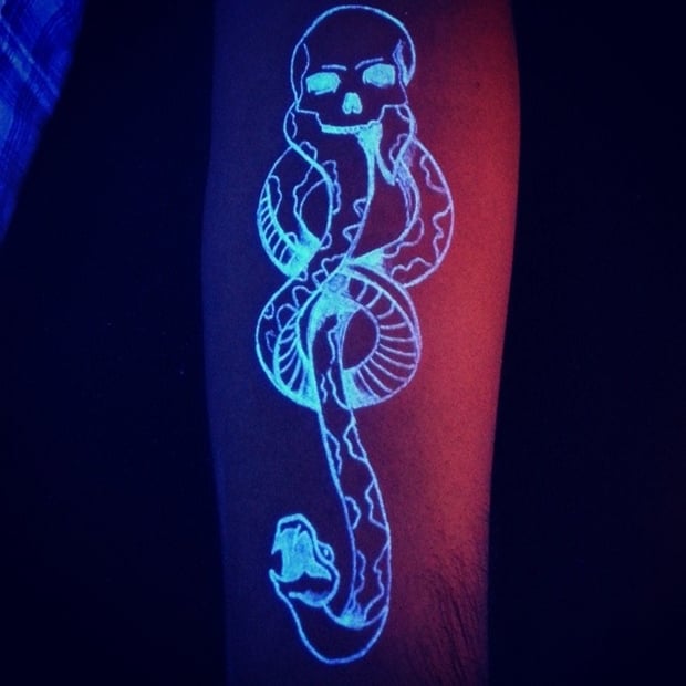 tatuaje que brilla en la oscuridad con el diseño de una calavera y una serpiente 