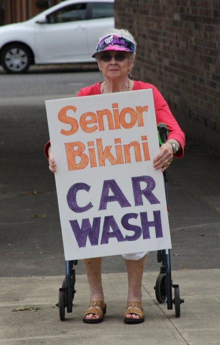 Abuela con letrero que dice lavado de autos para adultos mayores