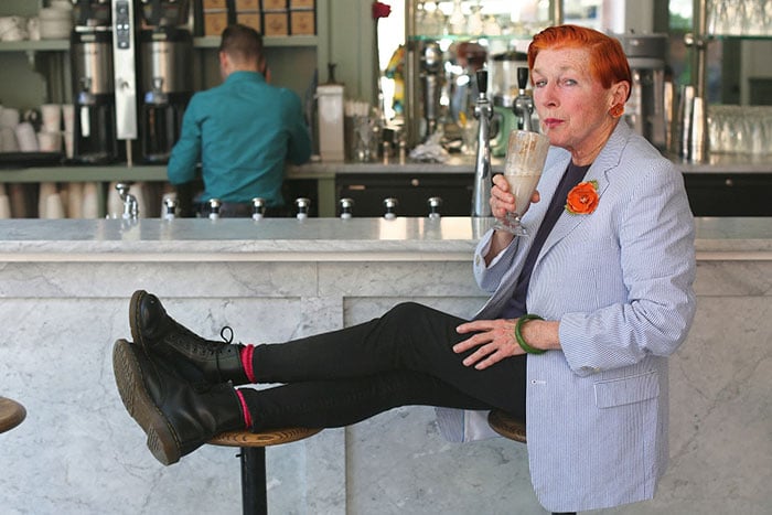 Mujer de +60 años con el cabello rojo, saco y botas y pantalón