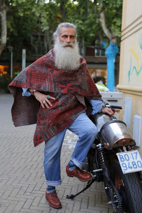 Hombre de +60 años con estilo hippie y barba blanca larga en una moto