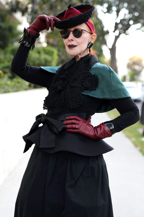 Mujer de +60 años con lentes, sombrero, guantes de piel, falda negra