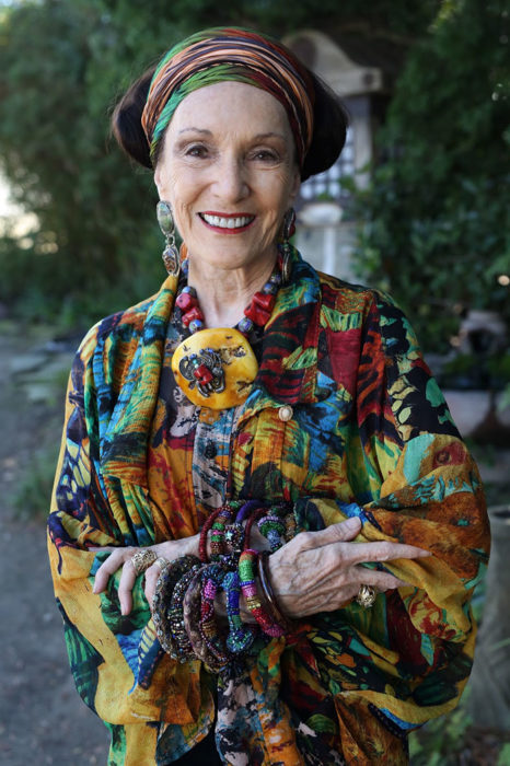 Mujer de +60 años sonriendo mientras luce muy elegante con ropa muy colorida