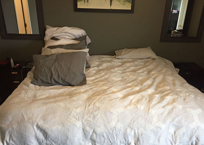 Hombre tiende la cama y se pone todas las almohadas para él