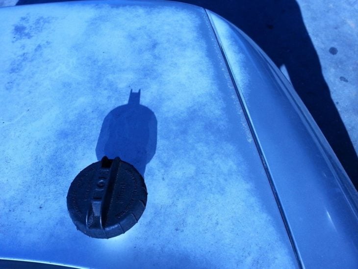 Fotografía de una tapa que con el reflejo del sol hace que aparezca una sombra de Batman