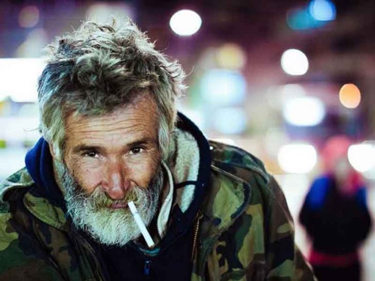Un vagabundo mira a la cámara mientras se fuma un cigarro
