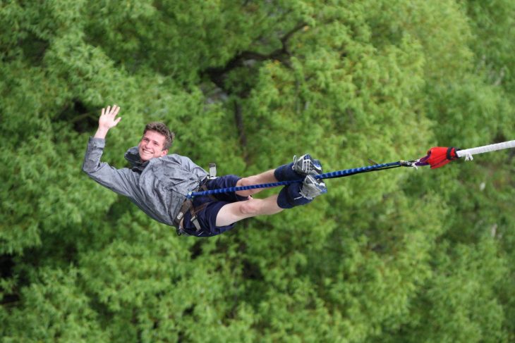 Un joven salta del bungee con una sonrisa y aspecto relajado