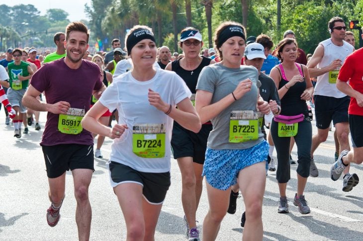 Fotografía de atletas en un maratón, un joven sonríe a la cámara y sale ridículamente guapo