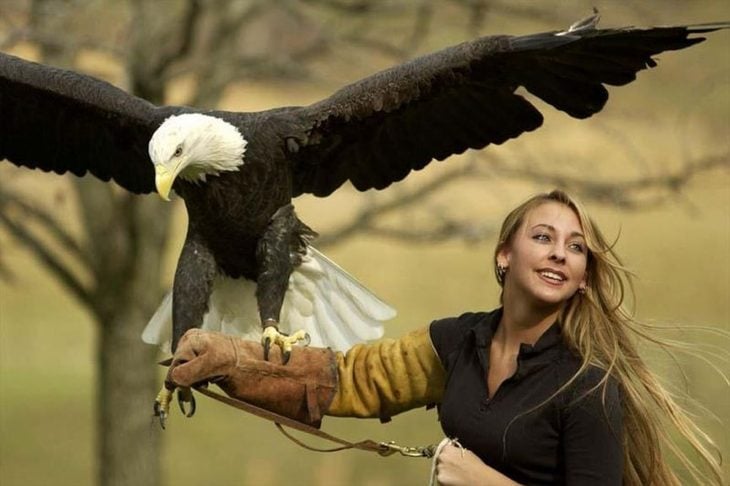 Una mujer le toman una fotografía mientras un águila real está en su muñeca