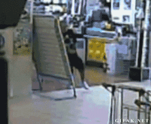 GIF de un ladrón que sale corriendo de una tienda en un centro comercial pero al llegar a la puerta se estampa con el vidrio y cae desmayado