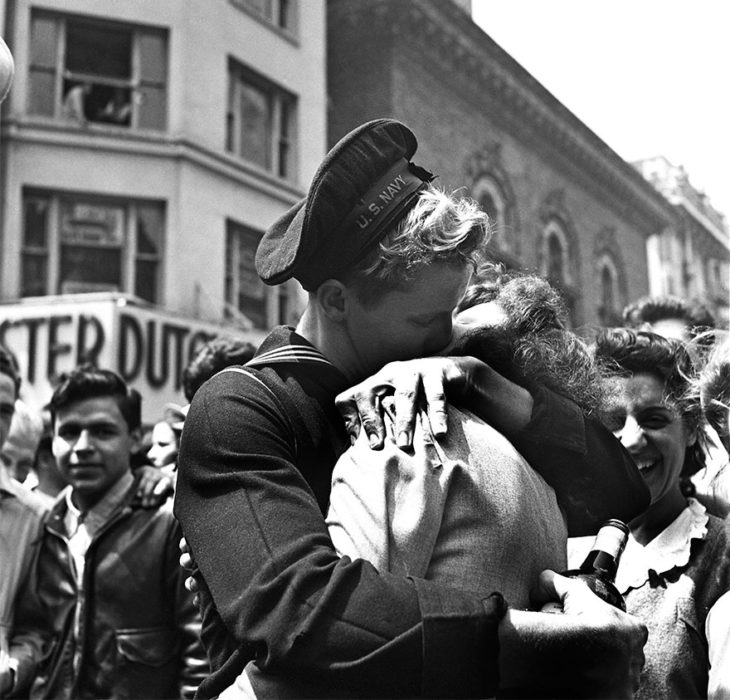 Amor en tiempos de guerra. soldado con una botella de vino abraza y besa a una mujer mientras otros ven