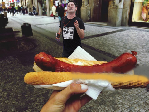 maratonista con tapón en la nariz corriendo hacia un hot dog