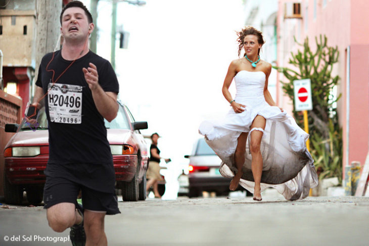 Maratonista con tapón en la nariz corriendo de una mujer vestida de novia