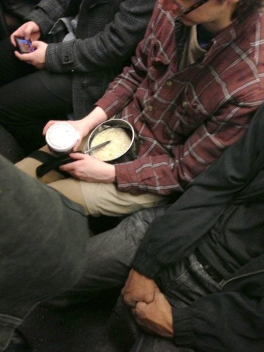 hombre con su desayuno en el metro