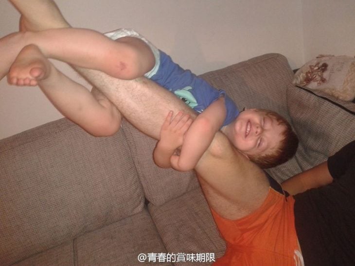 Niño en la pierna de su papá mientras él la levanta
