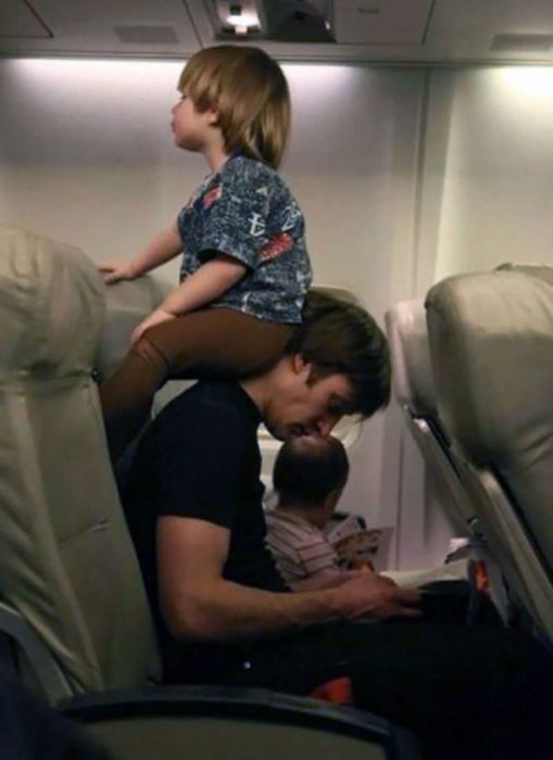Papá en avión, su hijo sentado en su cuello recargado en su cabeza