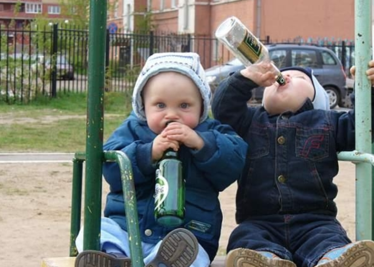 Niños pequeños tomando cerveza en columpio