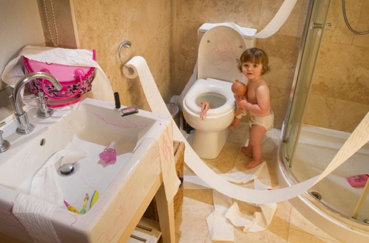 Niña en baño jugando con muñecas