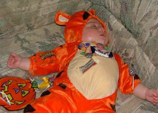 bebé dormido con muchos dulces, disfrazado de Tiger