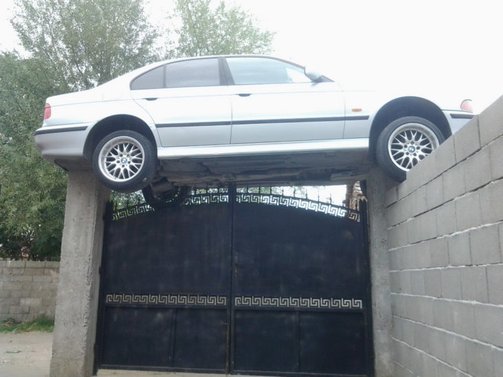 Fotos sin explicación. Un carro está "estacionado" encima de un portón