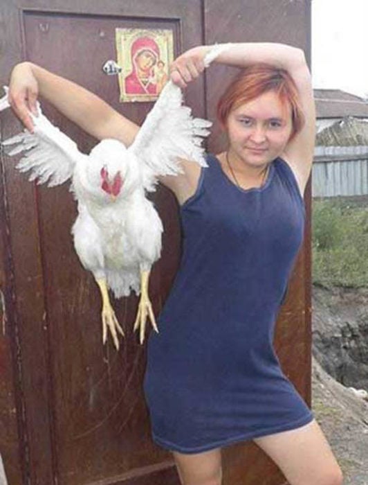 Mujer sosteniendo gallina por las alas