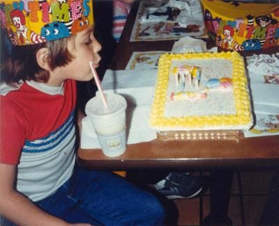 Niño soplando las velitas en su pastel de cumpleaños
