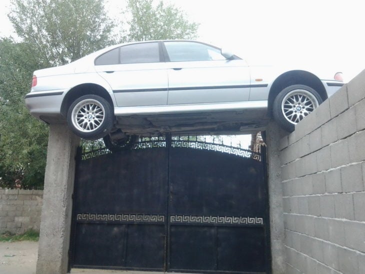 Fotos sin explicación. Un carro está "estacionado" encima de un portón 