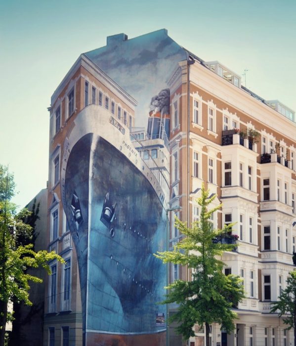 Graffitti en un edificio que asemeja un barco pasando entre dos edificios