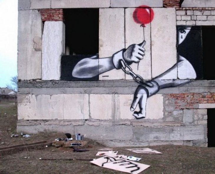 Graffitti de un niño con las manos atadas asomándose por una ventana 