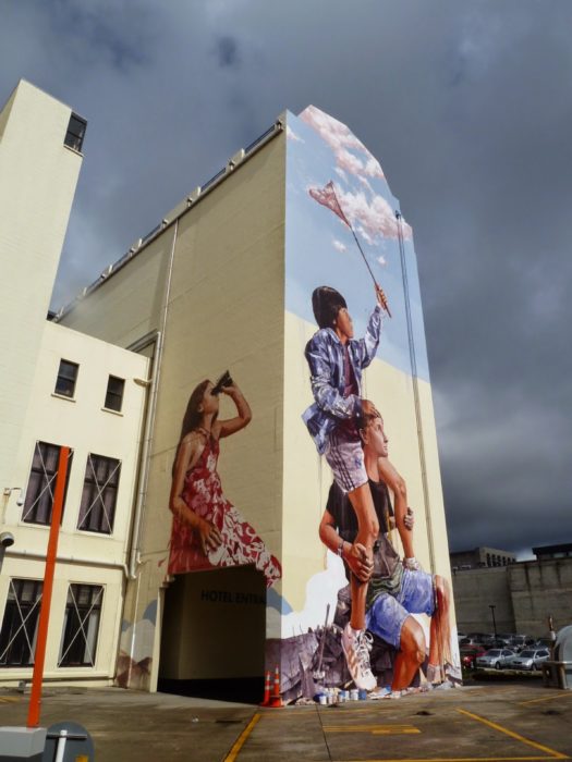 Graffitti de tres niños atrapando nubes