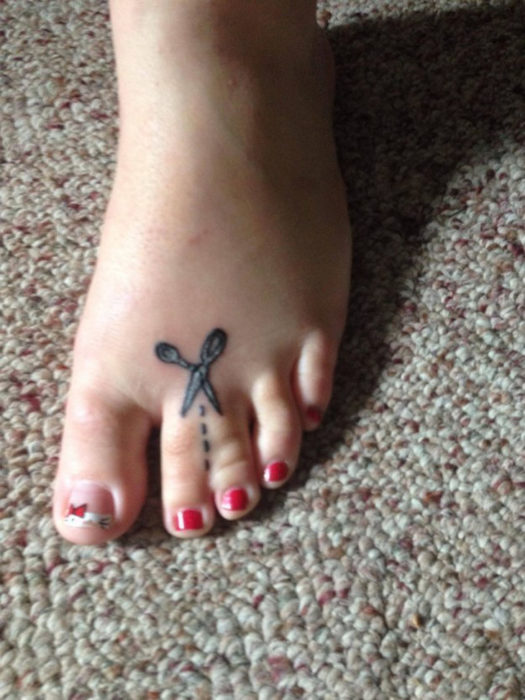Mujer con dos dedos del pie pegados y en ellos un tatuaje de una tijera