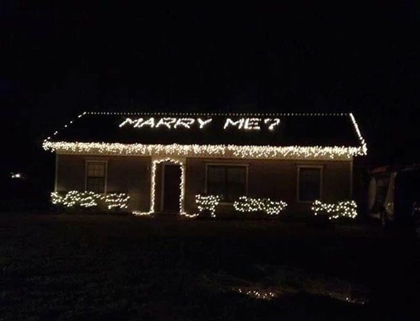 Propuesta, una casa con luces navideñas y en el techo iluminada las palabras marry me?