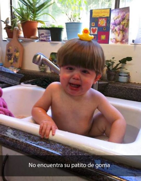 Niño dentro de un lavabo de cocina, bañandose