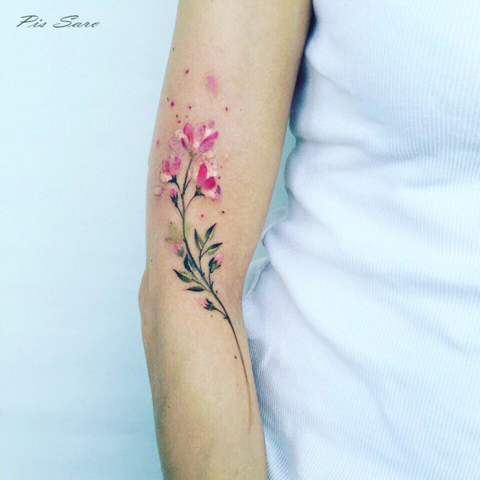 tatuje de una ramita con flores en un brazo