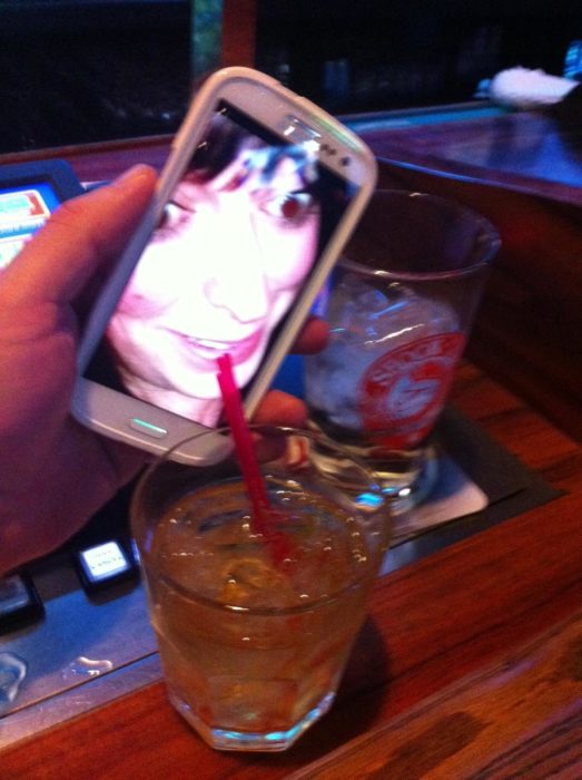 Mujer tomando de vaso en celular