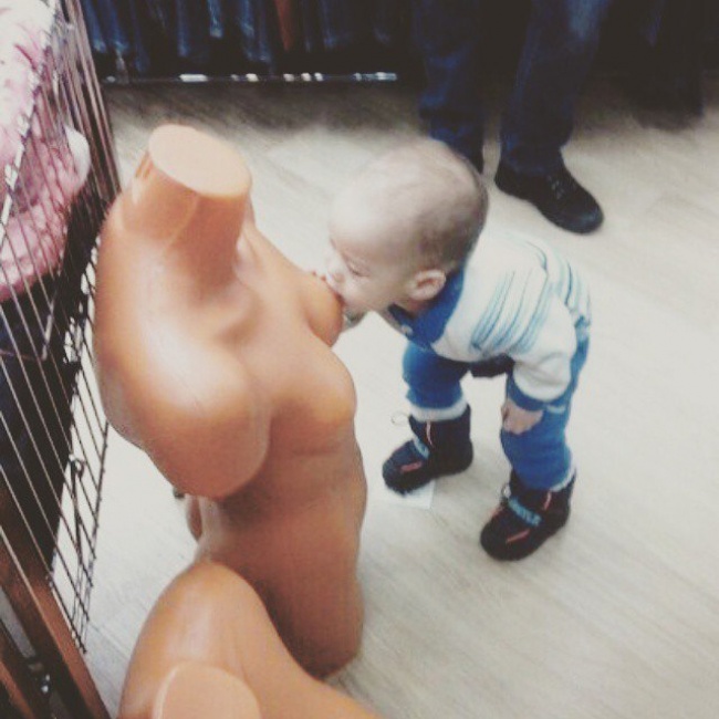 Niño pegado al pecho de un maniquí desnudo en una tienda