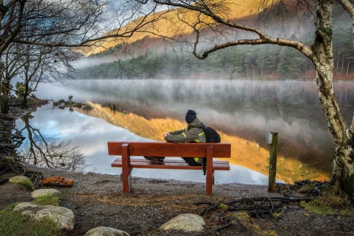 hombre sentado frente a un lago