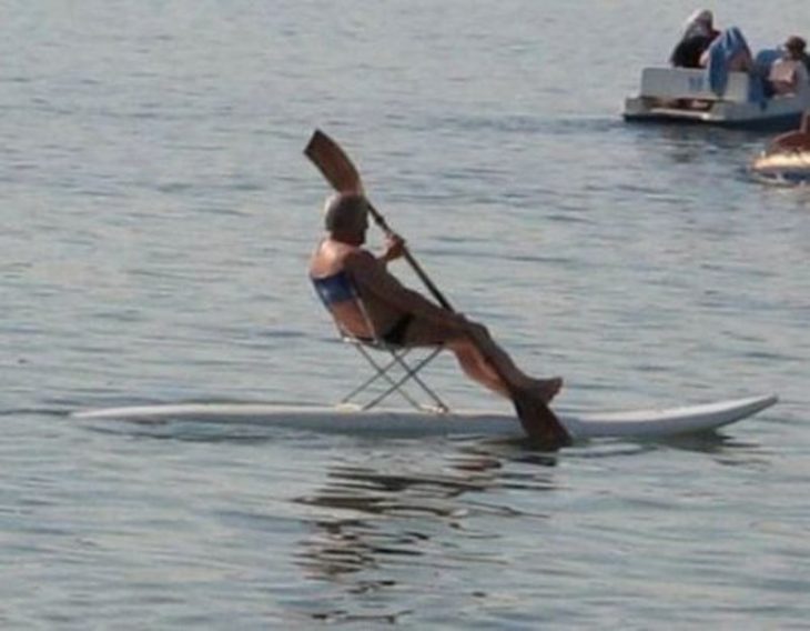 Hombre sentado en una silla arriba de una tabla de surf