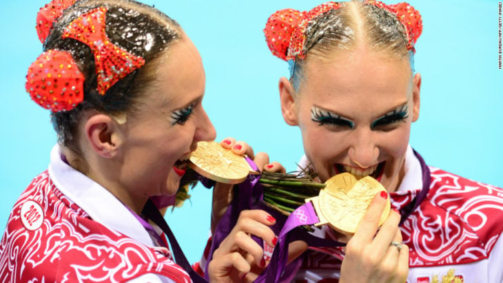 dos mujeres mordiendo sus medallas