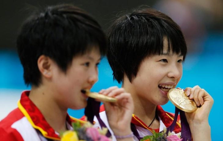 niños mordiendo medalla de oro