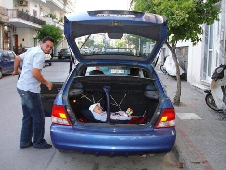 padre pone a su bebé en la cajuela del coche