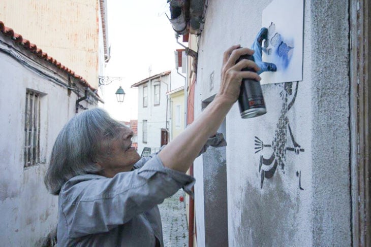 anciana hace graffiti en una pared