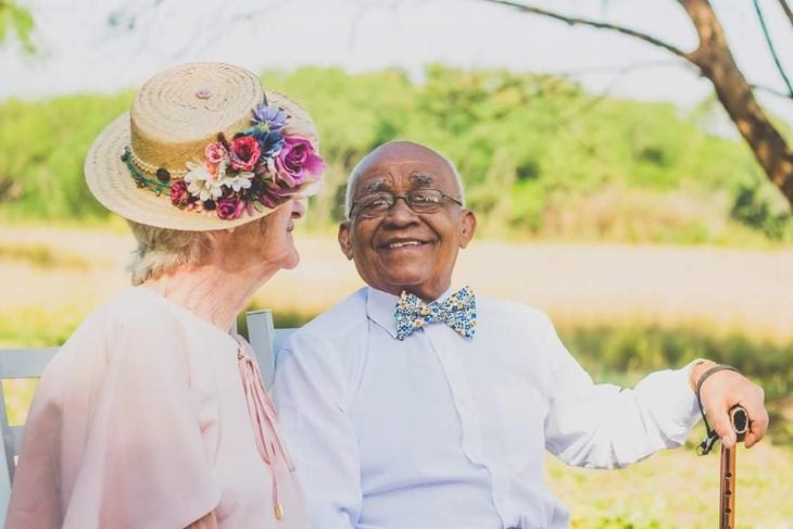 anciano sentado sonriendo a anciana que está a su lado