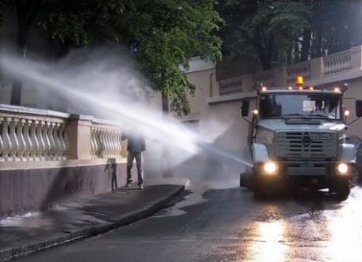 Hombre caminando lo llenan de agua un camión que riega las plantas