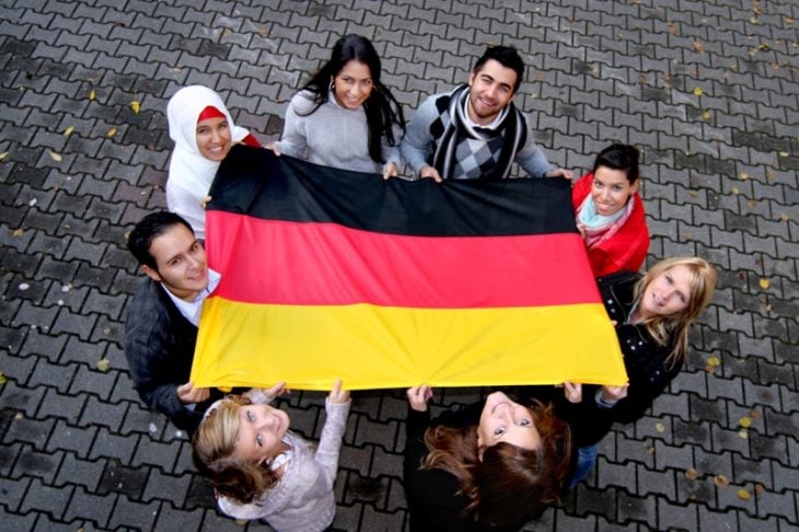 Estudiar en Alemania. Chicos sosteniendo una bandera de Alemania