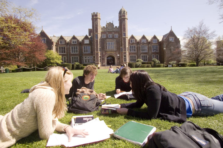 Estudiar en Estados Unidos. Chicos acostados en el cesped mientras estudian