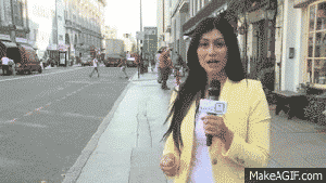 Una reportera en vivo mientras un ciclista cae atrás de ella de cara al piso